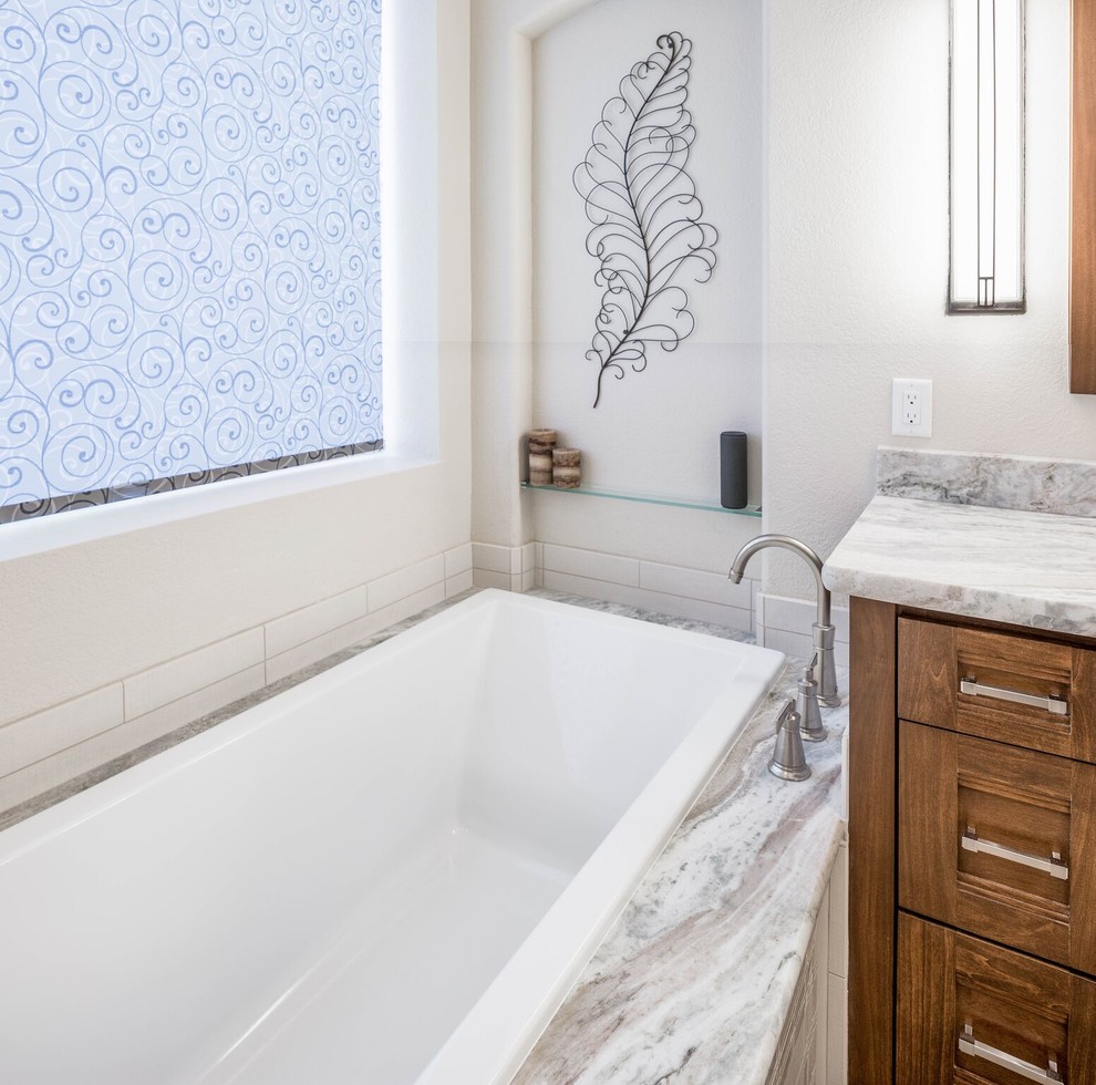 Example of a mid-sized transitional master gray tile and porcelain tile porcelain tile drop-in bathtub design in Phoenix with shaker cabinets, medium tone wood cabinets, a two-piece toilet, white walls, an undermount sink and granite countertops
