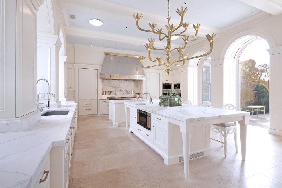 This is an example of a large transitional l-shaped eat-in kitchen in New York with an undermount sink, white cabinets, panelled appliances, with island, recessed-panel cabinets, marble benchtops, stone slab splashback, porcelain floors and beige floor.