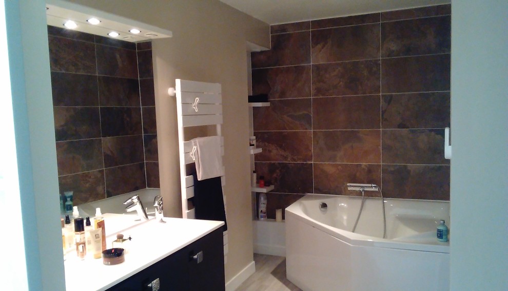 Cette image montre une salle de bain principale design de taille moyenne avec des portes de placard noires, une baignoire d'angle, un carrelage marron, un carrelage de pierre, un mur beige, un sol en linoléum et un lavabo de ferme.