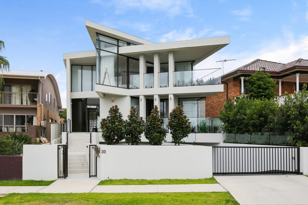 Photo of a mid-sized contemporary three-storey white townhouse exterior in Sydney with a flat roof.