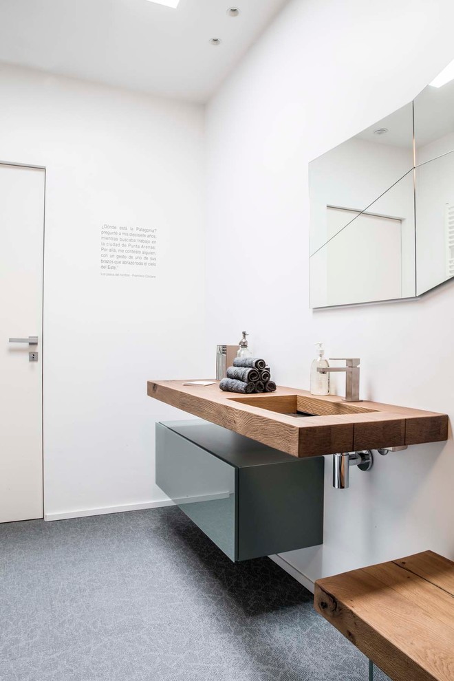 This is an example of a contemporary powder room in Turin with flat-panel cabinets, grey cabinets, a trough sink, wood benchtops and brown benchtops.