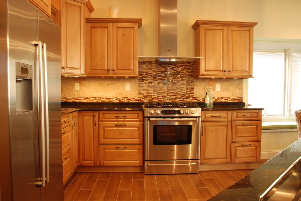 Mid-sized transitional l-shaped ceramic tile eat-in kitchen photo with a farmhouse sink, raised-panel cabinets, medium tone wood cabinets, granite countertops, beige backsplash, ceramic backsplash, stainless steel appliances and an island