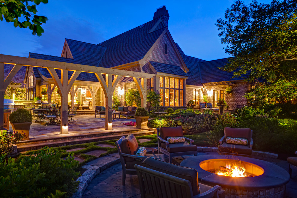 Photo of a large traditional backyard patio in Chicago with a fire feature, natural stone pavers and a pergola.