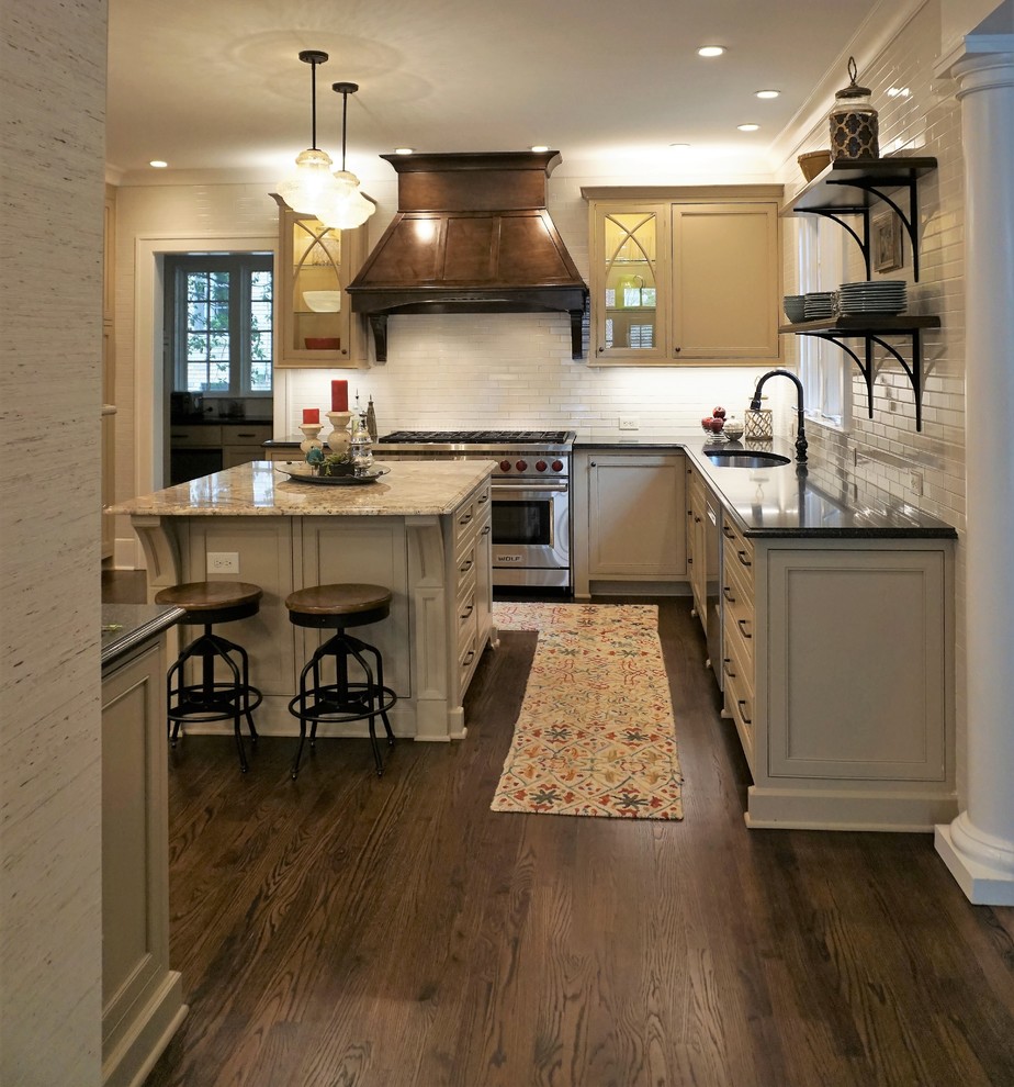 This is an example of a mid-sized traditional eat-in kitchen in Atlanta with a single-bowl sink, beaded inset cabinets, beige cabinets, granite benchtops, white splashback, ceramic splashback, stainless steel appliances, medium hardwood floors, with island, brown floor and multi-coloured benchtop.