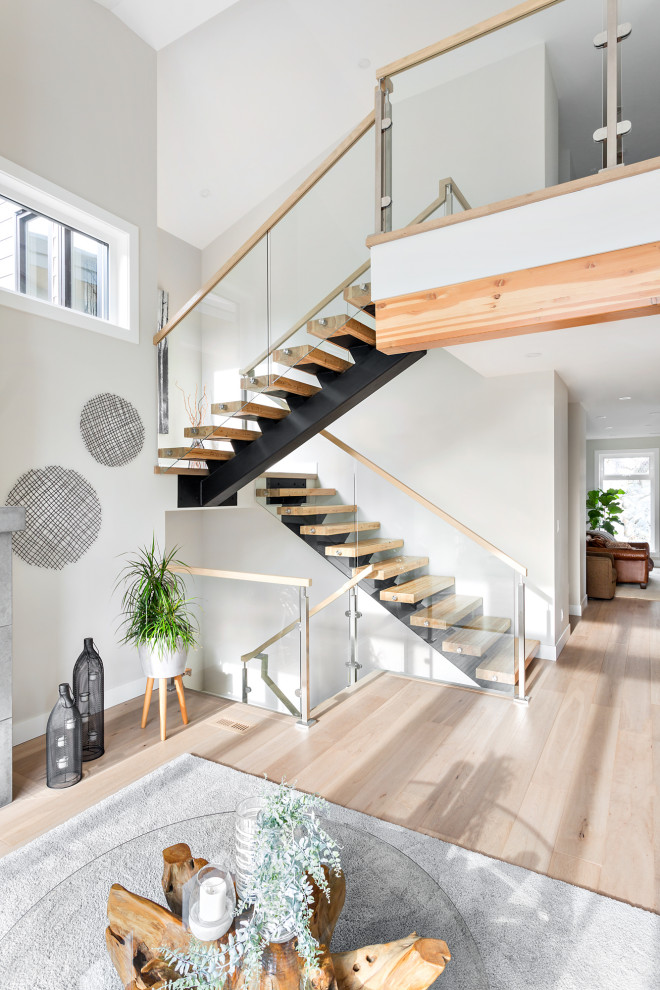 Photo of a contemporary wood u-shaped staircase in Vancouver with open risers and glass railing.