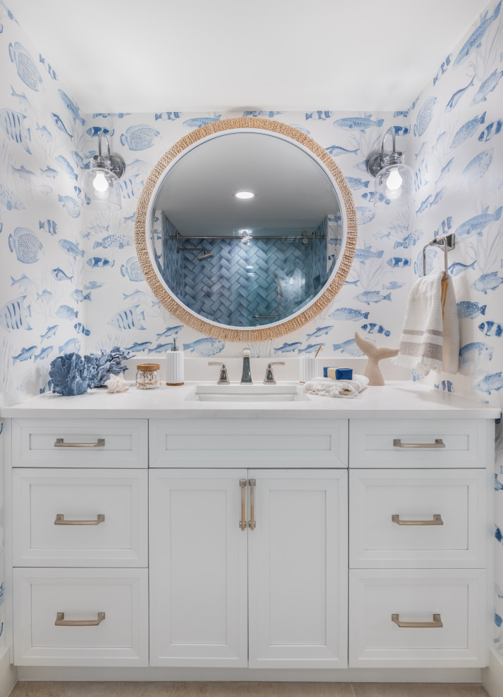 タンパにある高級な広いビーチスタイルのおしゃれなバスルーム (浴槽なし) (全タイプのキャビネット扉、白いキャビネット、ドロップイン型浴槽、シャワー付き浴槽	、青い壁、セラミックタイルの床、一体型シンク、御影石の洗面台、茶色い床、開き戸のシャワー、白い洗面カウンター、トイレ室、洗面台1つ、造り付け洗面台、壁紙) の写真