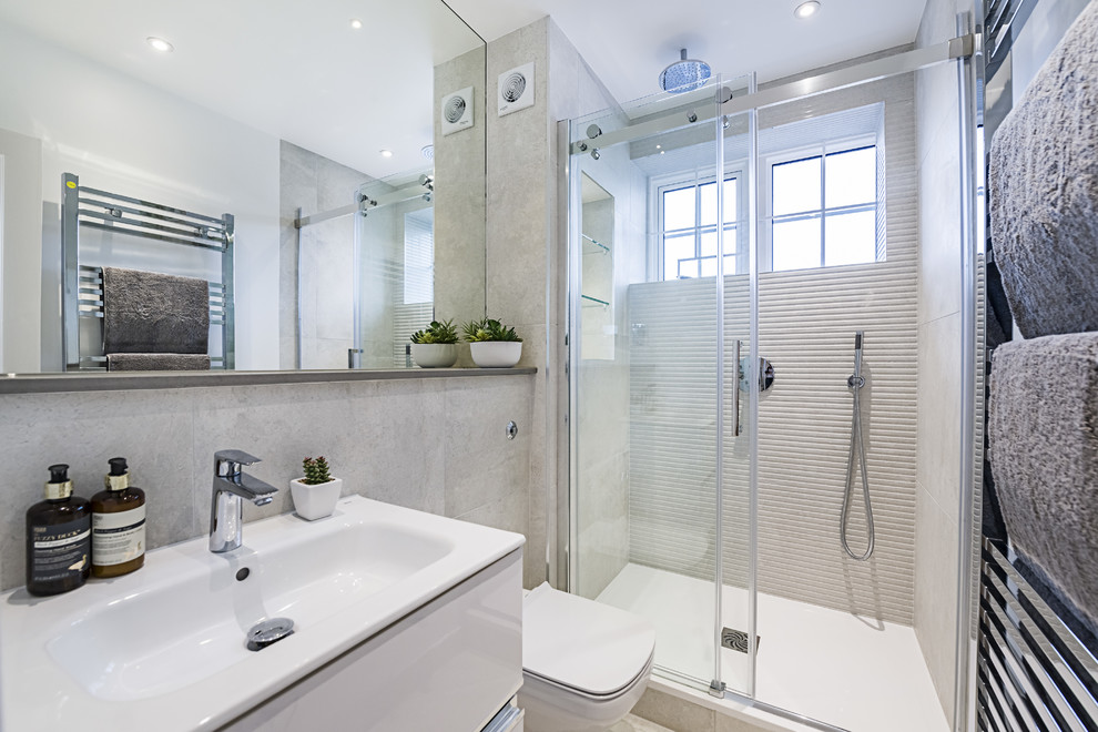 Inspiration for a small contemporary master bathroom in London with flat-panel cabinets, white cabinets, a curbless shower, a one-piece toilet, white tile, porcelain tile, porcelain floors, an integrated sink and a sliding shower screen.
