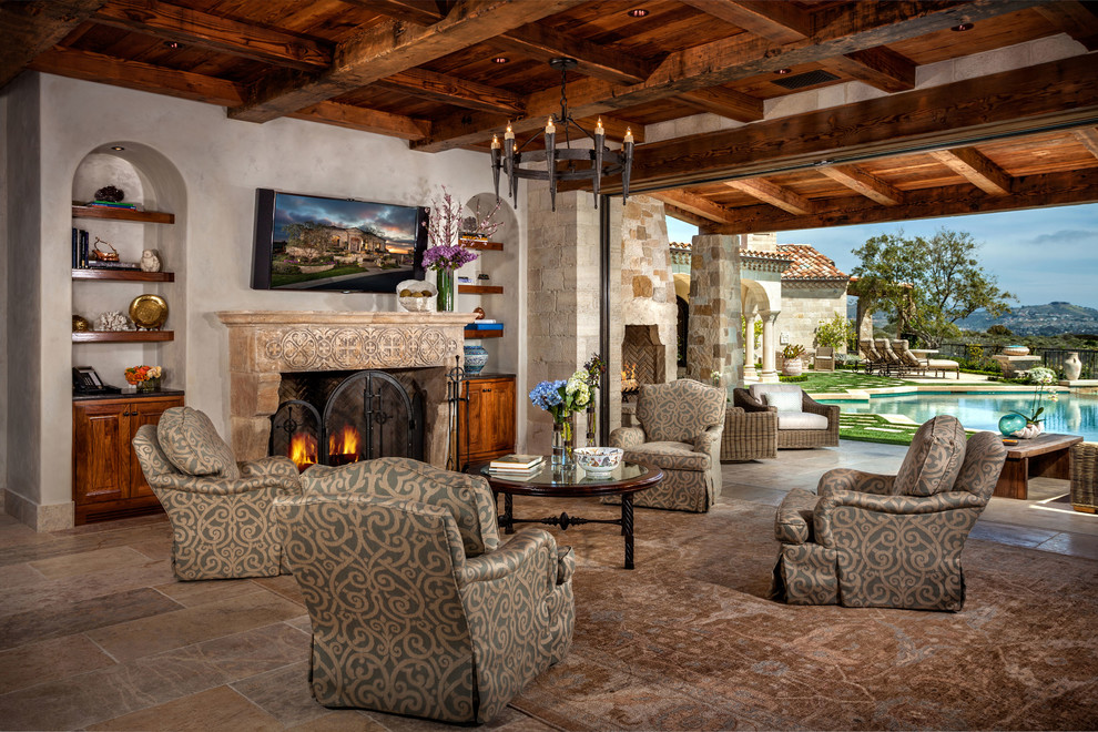 Mediterranean open concept family room in Orange County with beige walls, a standard fireplace, a wall-mounted tv and beige floor.