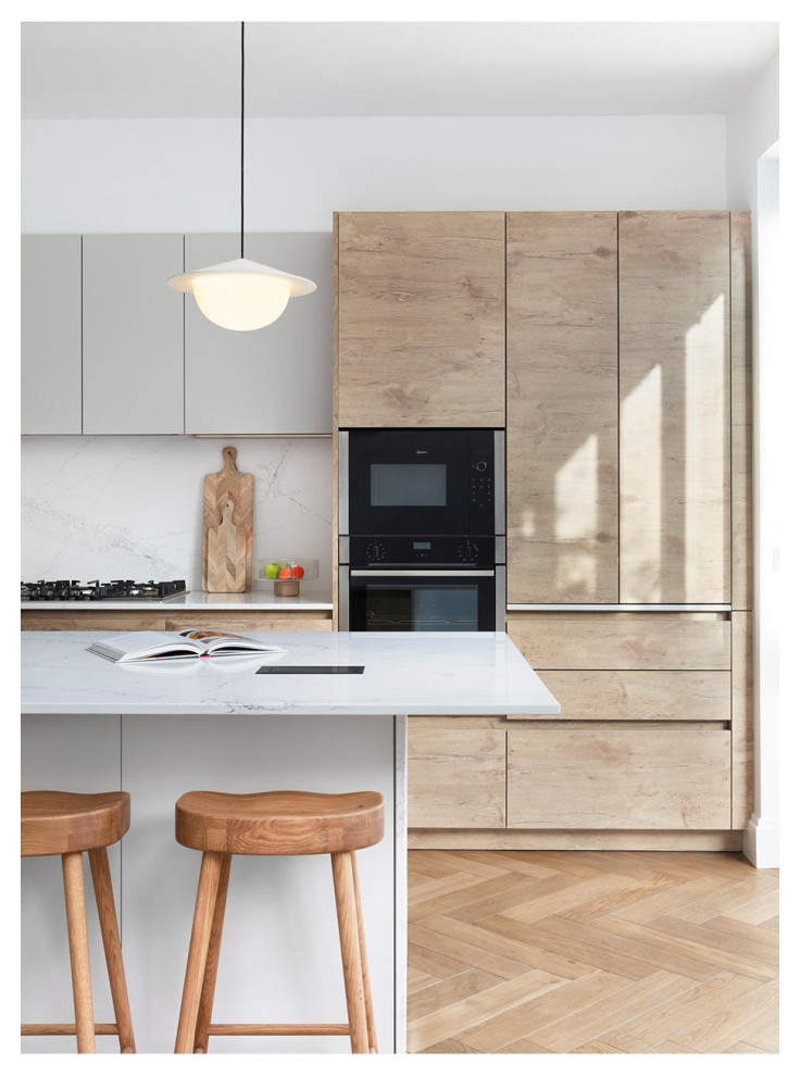 Photo of a large scandinavian open plan kitchen in London with an integrated sink, flat-panel cabinets, medium wood cabinets, quartzite benchtops, white splashback, engineered quartz splashback, stainless steel appliances, medium hardwood floors, with island, brown floor and white benchtop.