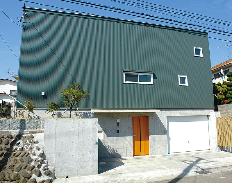 Foto della facciata di una casa verde moderna a piani sfalsati di medie dimensioni con rivestimento in metallo, copertura in metallo o lamiera, tetto grigio e pannelli e listelle di legno