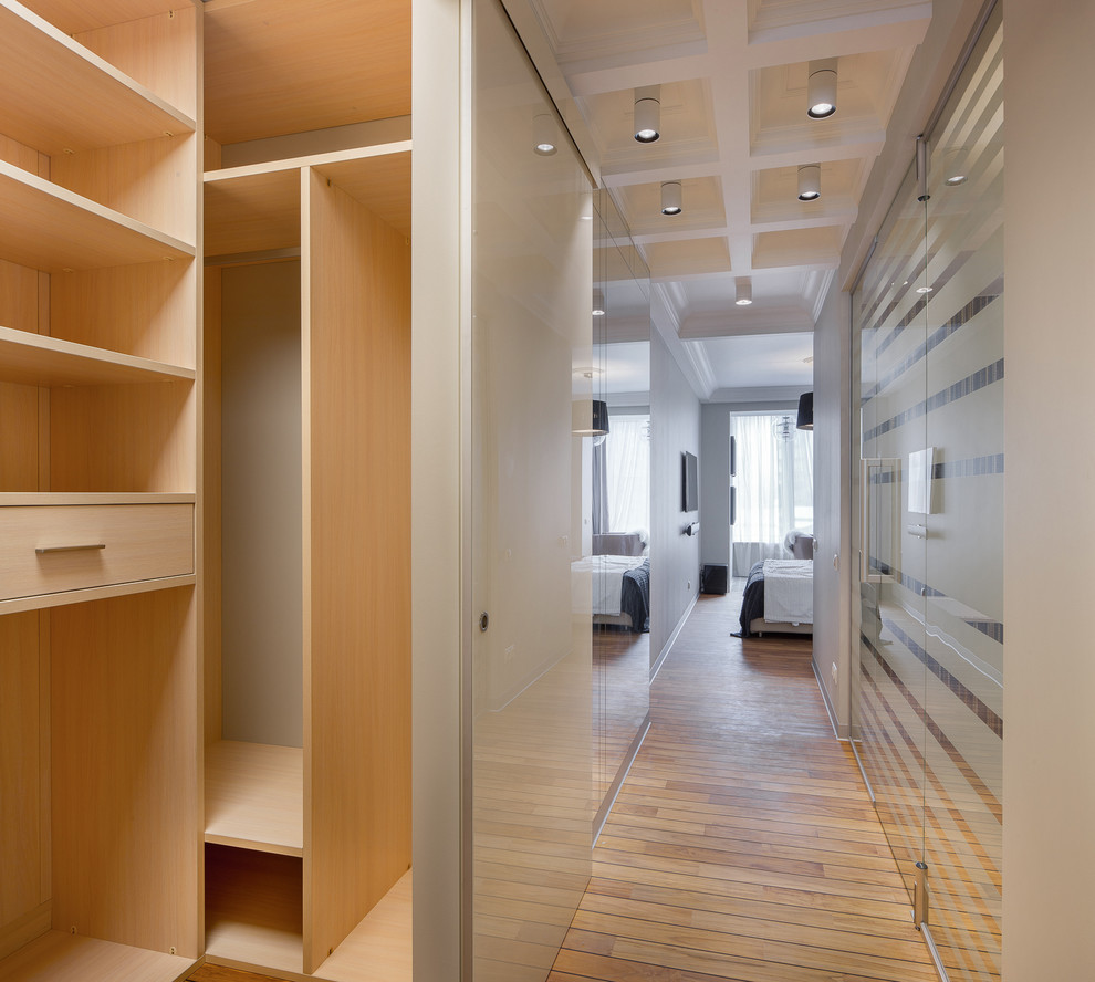 Photo of a contemporary gender-neutral built-in wardrobe in Other with flat-panel cabinets and light wood cabinets.