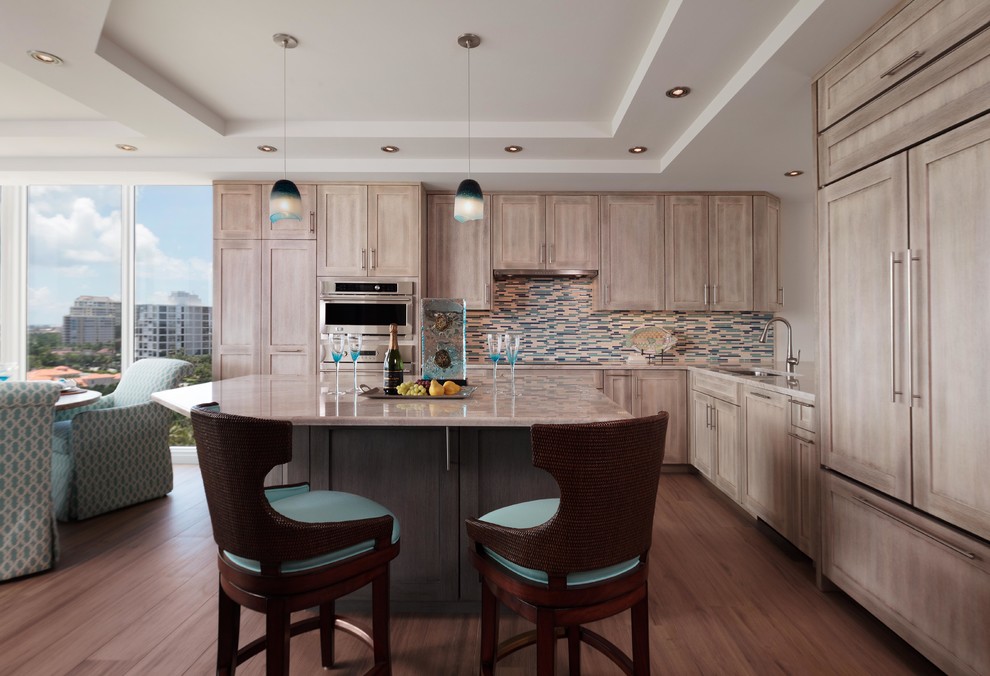 Beach style l-shaped eat-in kitchen in Tampa with an undermount sink, recessed-panel cabinets, distressed cabinets, granite benchtops, blue splashback, mosaic tile splashback, panelled appliances, medium hardwood floors and with island.
