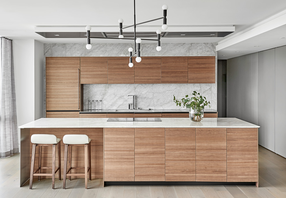 Design ideas for a small contemporary galley open plan kitchen in Chicago with an integrated sink, flat-panel cabinets, medium wood cabinets, quartzite benchtops, grey splashback, stone slab splashback, panelled appliances, with island, white benchtop, light hardwood floors and beige floor.