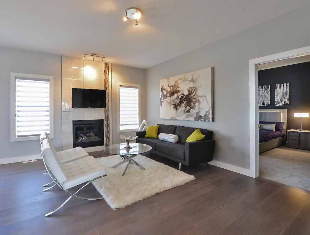 Inspiration for a small contemporary open concept living room in Edmonton with grey walls, dark hardwood floors, a standard fireplace, a tile fireplace surround and a wall-mounted tv.