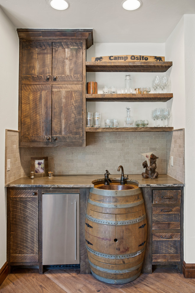 This is an example of a small country wet bar in Other with a drop-in sink, distressed cabinets and granite benchtops.