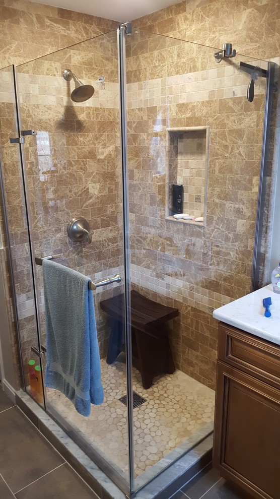 Medium sized classic bathroom in Providence with raised-panel cabinets, medium wood cabinets, a corner shower, a submerged sink, a hinged door, beige tiles, stone tiles, porcelain flooring, marble worktops and brown floors.