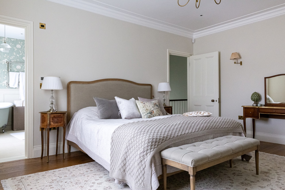 Photo of a traditional bedroom in London with beige walls, brown floor and dark hardwood floors.