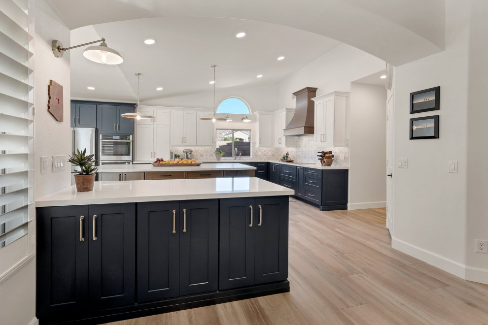 Large transitional l-shaped porcelain tile, brown floor and vaulted ceiling eat-in kitchen photo in Phoenix with an undermount sink, shaker cabinets, blue cabinets, quartzite countertops, multicolored backsplash, mosaic tile backsplash, stainless steel appliances, two islands and white countertops