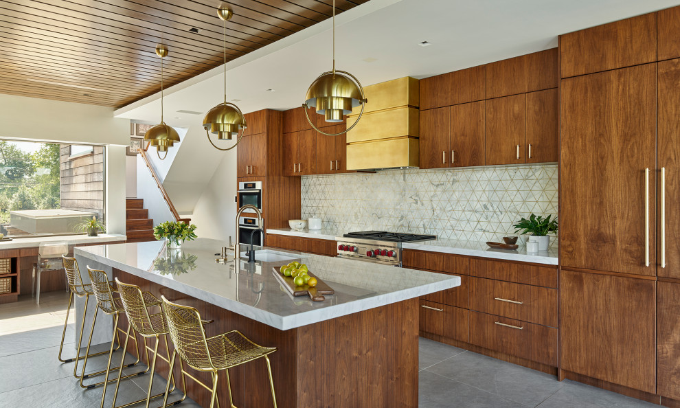 Inspiration for a midcentury kitchen in Philadelphia with an undermount sink, flat-panel cabinets, medium wood cabinets, marble benchtops, white splashback, marble splashback, stainless steel appliances, porcelain floors, with island, grey floor, white benchtop and wood.