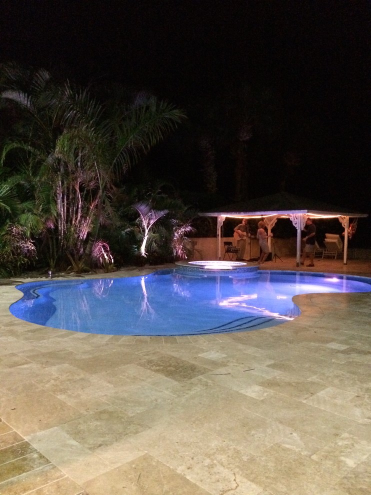 This is an example of a mid-sized traditional backyard custom-shaped lap pool in Tampa with a pool house and tile.