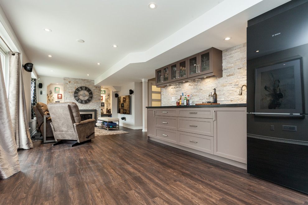 This is an example of a large contemporary single-wall wet bar in Toronto with an undermount sink, shaker cabinets, beige cabinets, quartz benchtops, beige splashback, stone tile splashback, dark hardwood floors and brown floor.