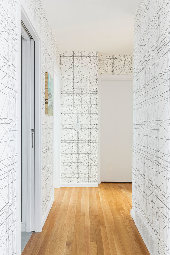 Photo of a mid-sized midcentury hallway in Portland with white walls, light hardwood floors and beige floor.