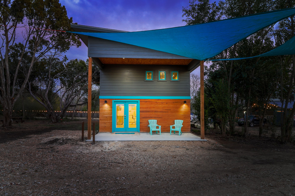 Exemple d'une petite façade de Tiny House bleue éclectique en planches et couvre-joints à un étage avec un revêtement mixte, un toit en appentis, un toit en métal et un toit gris.