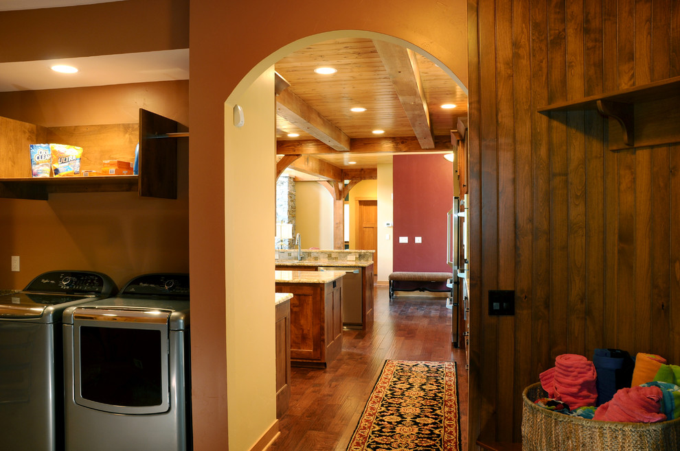 This is an example of a mid-sized country u-shaped utility room in Other with dark wood cabinets, granite benchtops, slate floors, a side-by-side washer and dryer, recessed-panel cabinets and orange walls.
