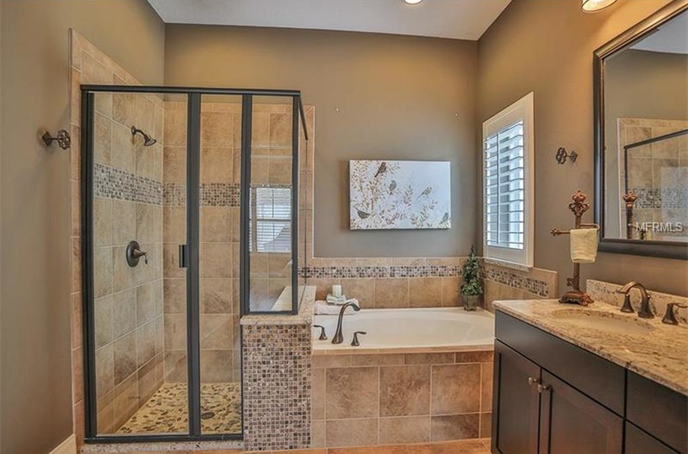 Inspiration for a mid-sized traditional 3/4 bathroom in Orlando with shaker cabinets, dark wood cabinets, a drop-in tub, an alcove shower, a two-piece toilet, beige tile, brown tile, ceramic tile, brown walls, an undermount sink, granite benchtops and a hinged shower door.