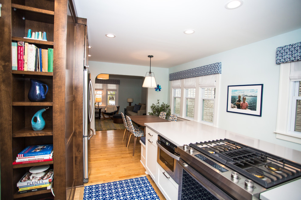 Enclosed kitchen - mid-sized transitional galley light wood floor enclosed kitchen idea in Milwaukee with an undermount sink, shaker cabinets, medium tone wood cabinets, quartz countertops, blue backsplash, ceramic backsplash, stainless steel appliances and an island