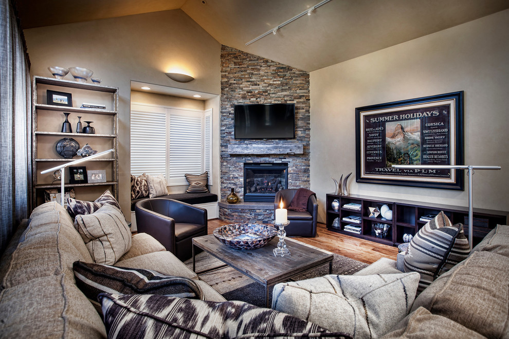 This is an example of a mid-sized transitional open concept living room in Denver with beige walls, medium hardwood floors, a standard fireplace, a stone fireplace surround, a wall-mounted tv and beige floor.