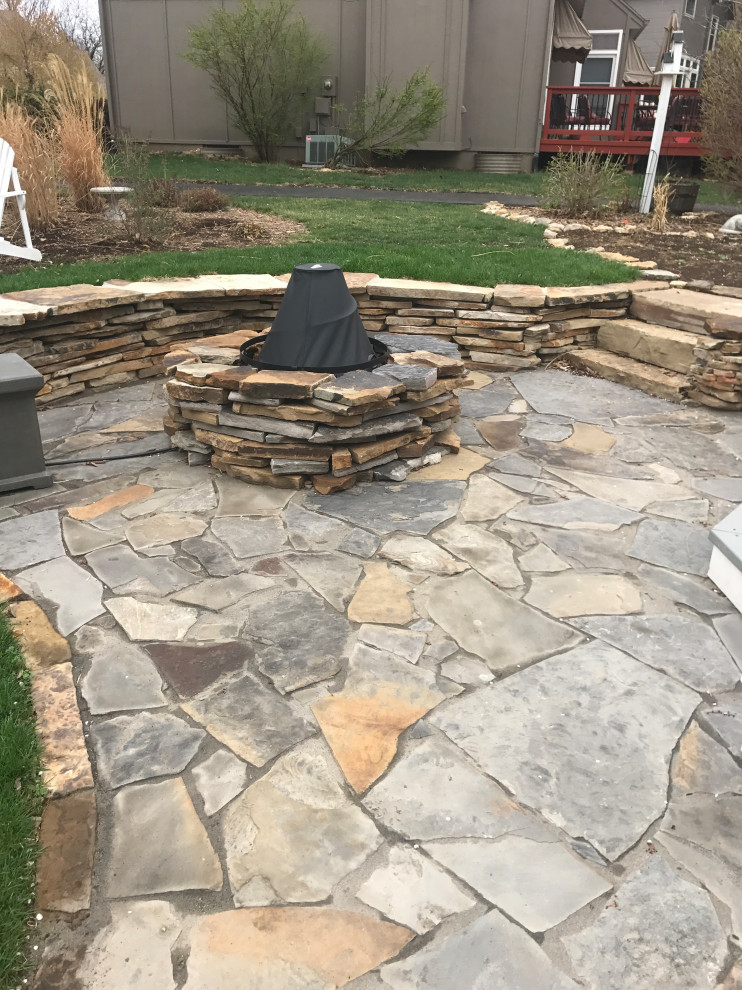 This is an example of a large traditional backyard full sun formal garden for spring in Kansas City with a fire feature and natural stone pavers.
