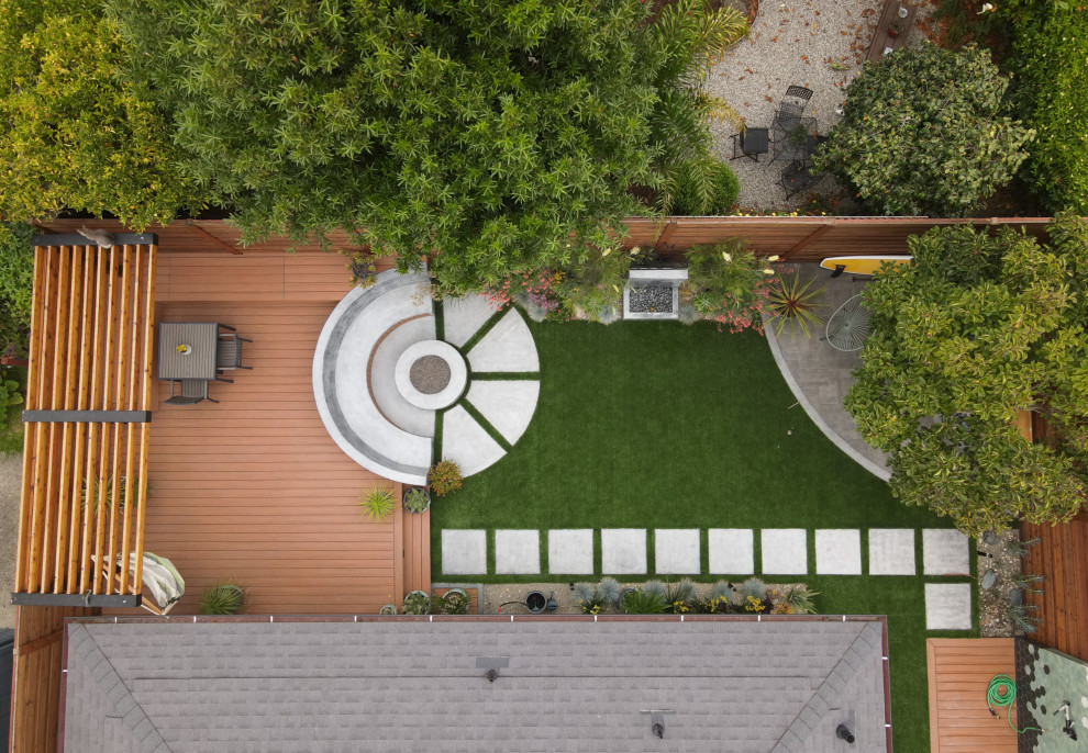 Esempio di un giardino xeriscape minimalista esposto in pieno sole di medie dimensioni e dietro casa in estate con un focolare, pavimentazioni in cemento e recinzione in legno