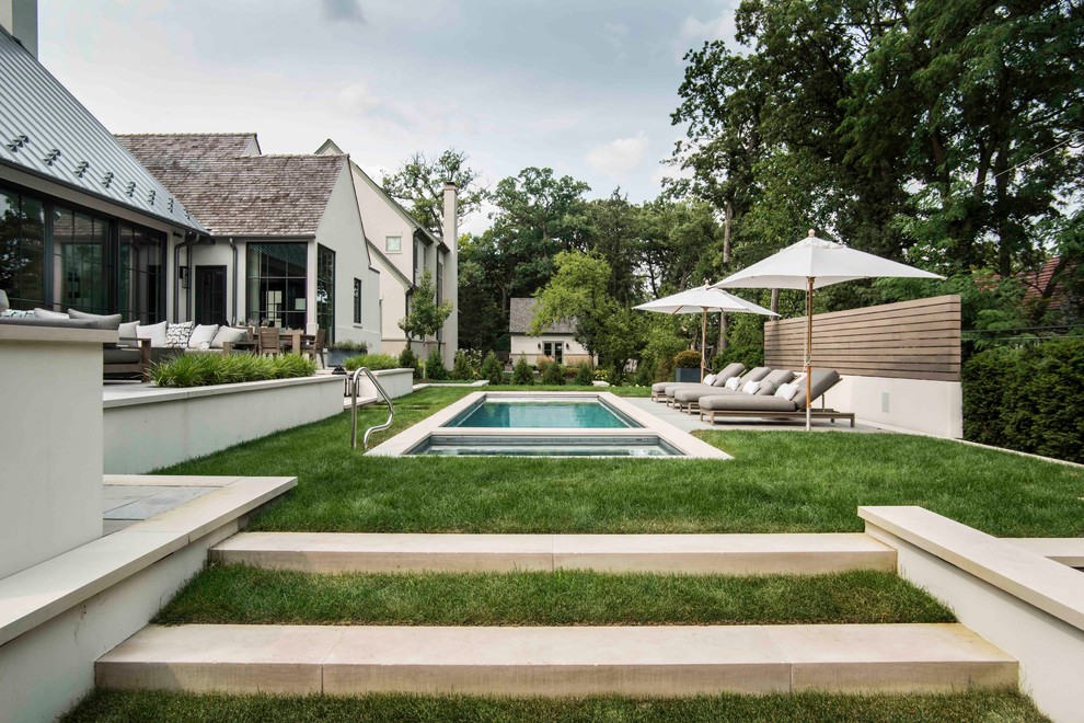 This is an example of a mid-sized traditional backyard rectangular lap pool in Chicago with a hot tub and natural stone pavers.