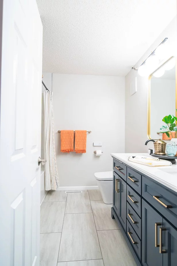 This is an example of a small transitional master bathroom in Minneapolis with shaker cabinets, blue cabinets, an alcove tub, a shower/bathtub combo, a bidet, white tile, ceramic tile, white walls, an undermount sink, engineered quartz benchtops, beige floor, a shower curtain, white benchtops, a double vanity and a freestanding vanity.