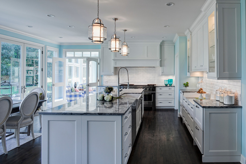 Large traditional eat-in kitchen in Chicago with white cabinets, marble benchtops, stainless steel appliances, with island, a farmhouse sink, shaker cabinets, white splashback, subway tile splashback and dark hardwood floors.