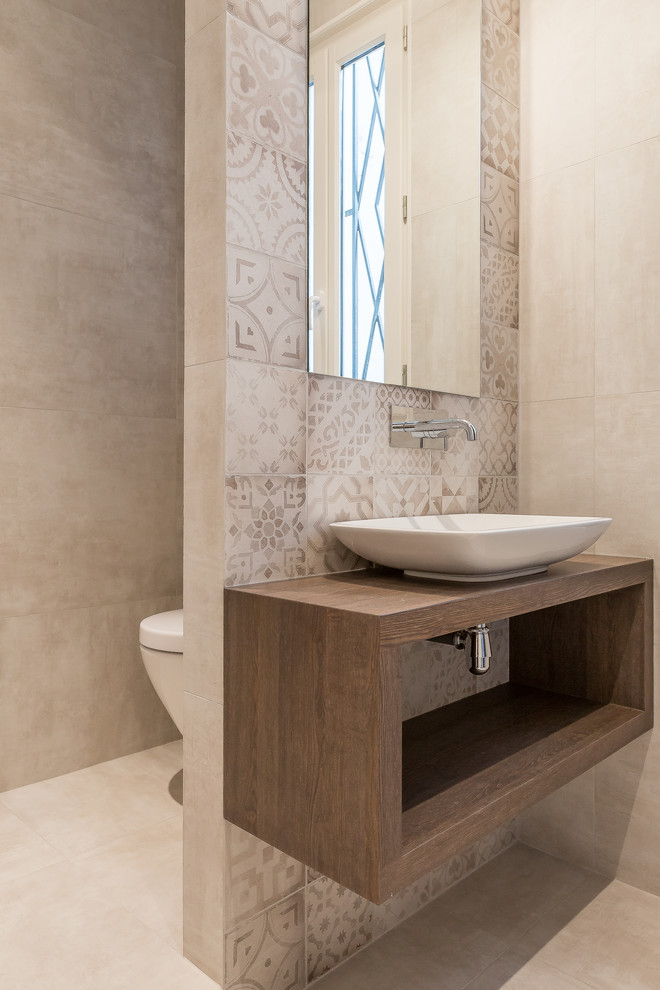 This is an example of a mid-sized contemporary master bathroom in Paris with a vessel sink, open cabinets, wood benchtops, a wall-mount toilet, beige tile, cement tile, beige walls and brown benchtops.