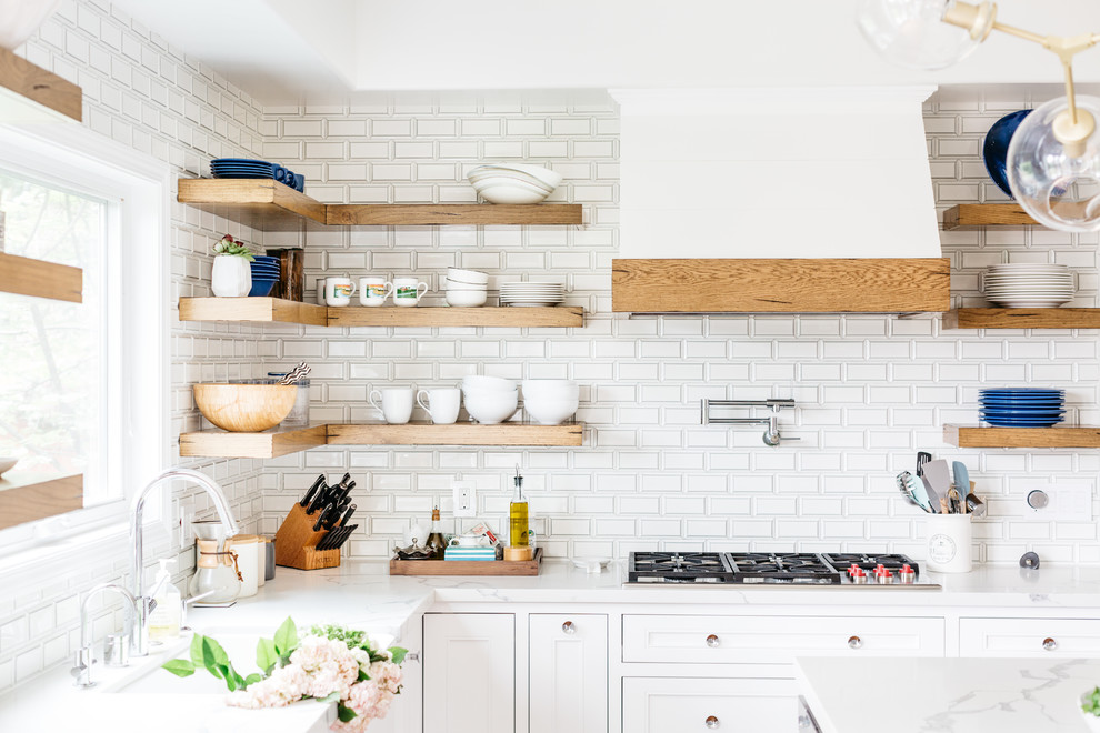 Inspiration for a mid-sized transitional u-shaped medium tone wood floor and brown floor eat-in kitchen remodel in Los Angeles with a farmhouse sink, recessed-panel cabinets, white cabinets, quartzite countertops, white backsplash, subway tile backsplash, stainless steel appliances, an island and white countertops