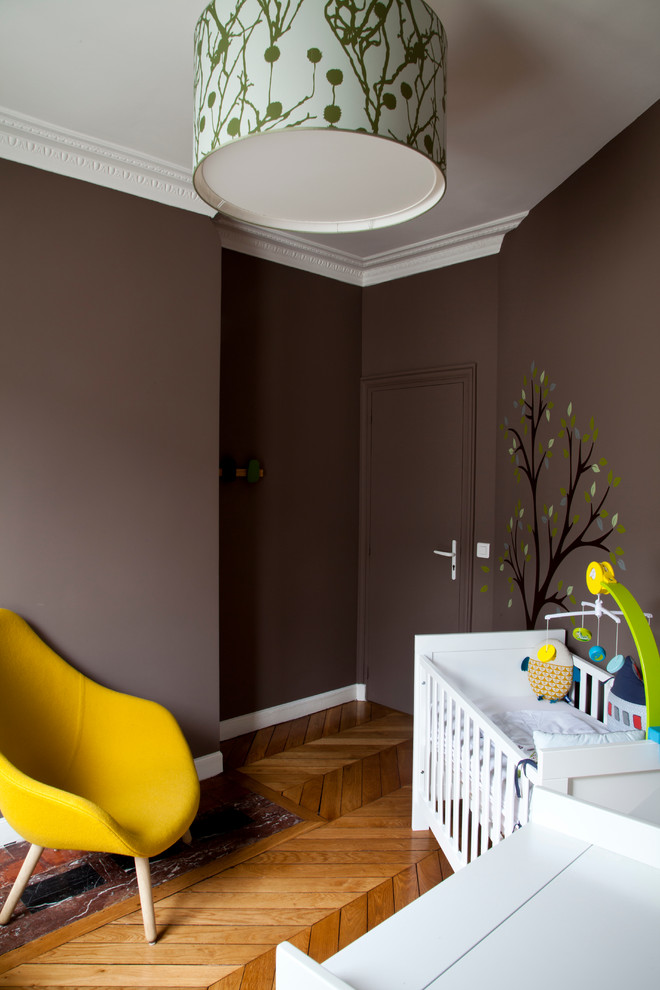Design ideas for a mid-sized contemporary gender-neutral nursery in Paris with brown walls and medium hardwood floors.