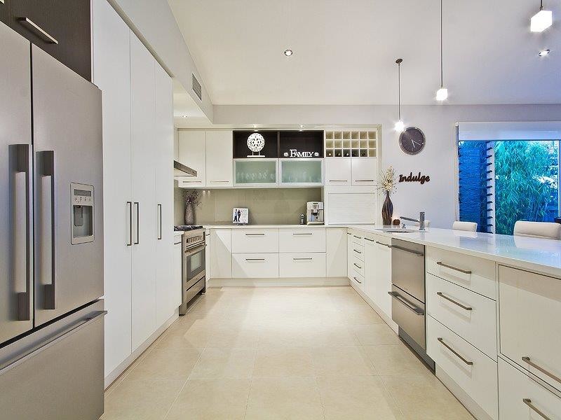 This is an example of a mid-sized contemporary u-shaped eat-in kitchen in Brisbane with an undermount sink, white cabinets, quartz benchtops, beige splashback, glass sheet splashback, stainless steel appliances and porcelain floors.