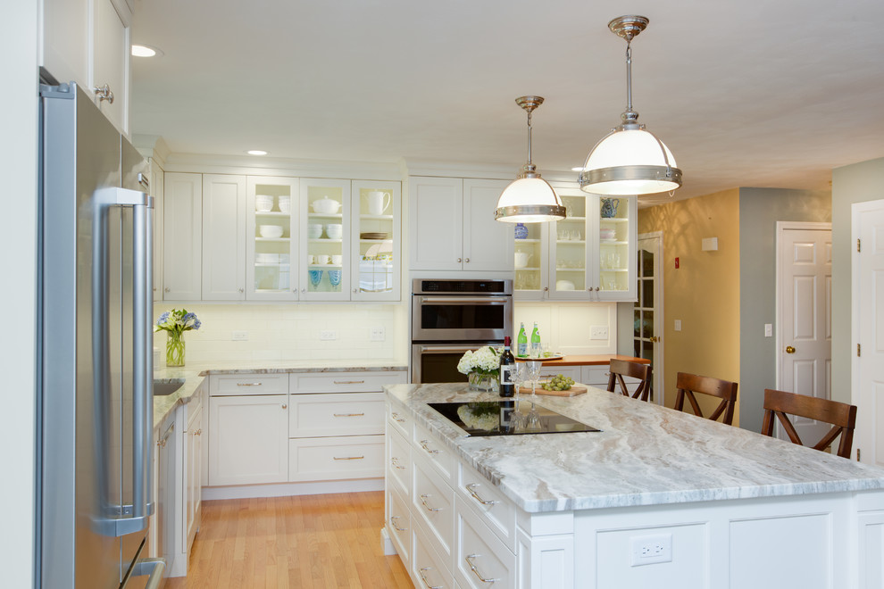 Example of a transitional l-shaped light wood floor eat-in kitchen design in Boston with an undermount sink, recessed-panel cabinets, white cabinets, quartzite countertops, white backsplash, subway tile backsplash, stainless steel appliances and an island
