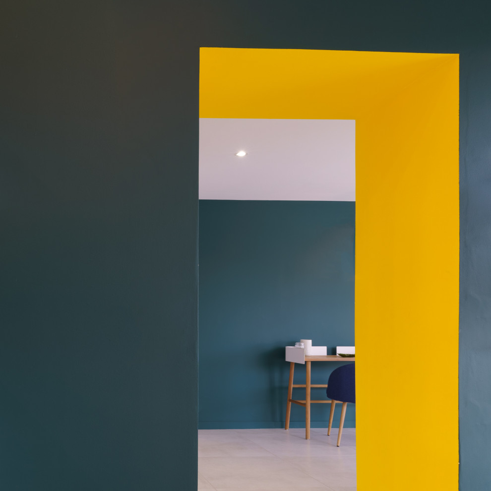 Inredning av ett skandinaviskt stort arbetsrum, med gula väggar, klinkergolv i keramik, ett fristående skrivbord och grått golv