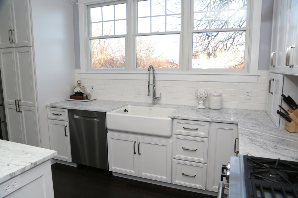 Inspiration for a large transitional l-shaped dark wood floor eat-in kitchen remodel in Chicago with recessed-panel cabinets, stainless steel appliances, an island, a farmhouse sink, white cabinets, quartz countertops, white backsplash and subway tile backsplash