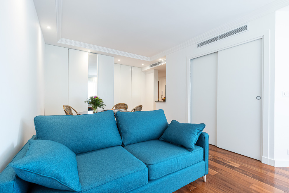 Modelo de salón abierto, blanco y blanco y madera clásico renovado de tamaño medio con paredes blancas, suelo de madera en tonos medios, televisor independiente y suelo beige