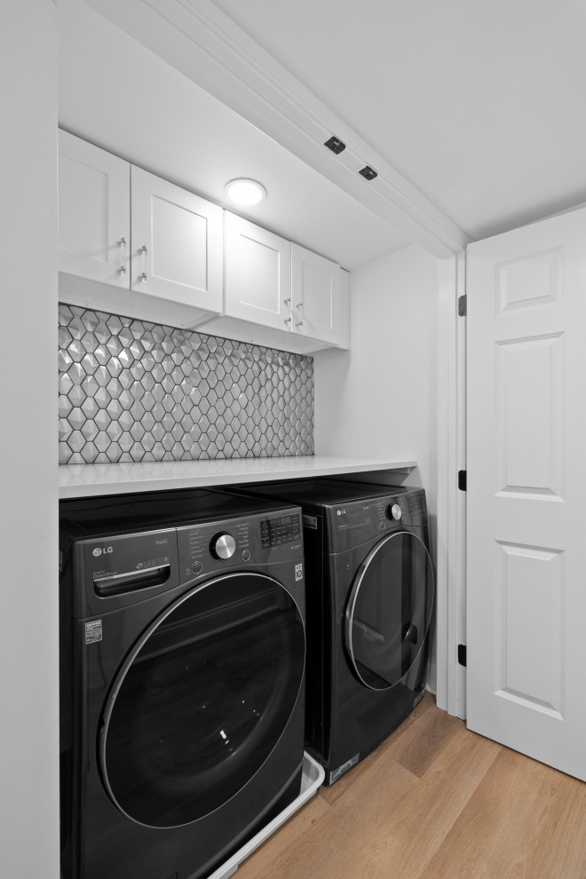 Idéer för att renovera en funkis liten tvättstuga, med vita skåp, bänkskiva i kvartsit, stänkskydd i metallkakel och en tvättmaskin och torktumlare bredvid varandra
