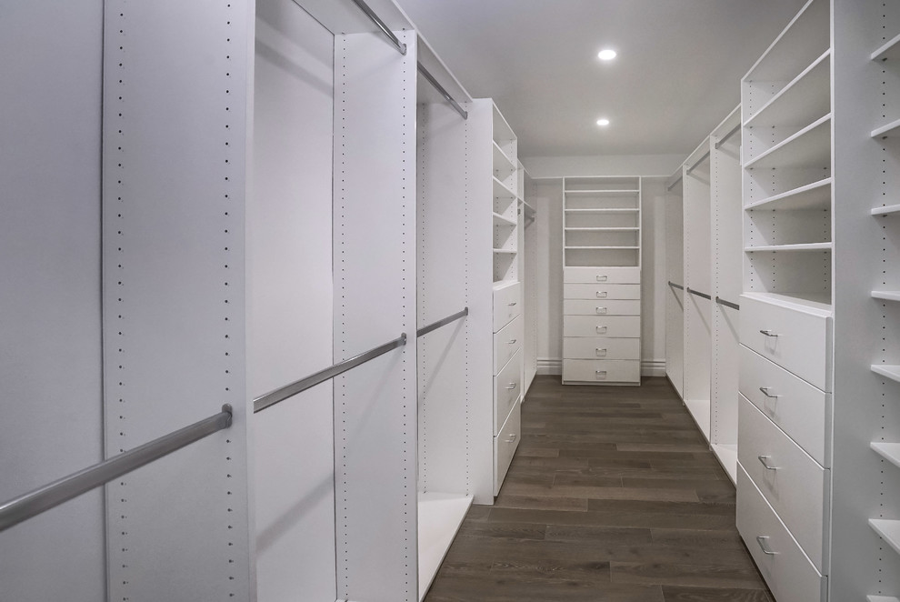 Mid-sized midcentury gender-neutral walk-in wardrobe in Los Angeles with flat-panel cabinets, white cabinets, dark hardwood floors and brown floor.