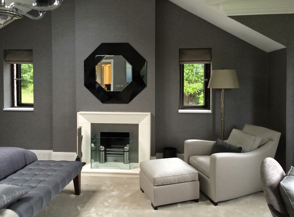 This is an example of a large arts and crafts master bedroom in Cornwall with grey walls, carpet, a standard fireplace, a stone fireplace surround, beige floor and wallpaper.