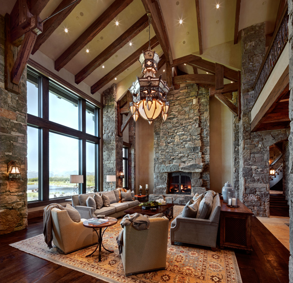 Mountain style open concept dark wood floor, brown floor, exposed beam and vaulted ceiling living room photo in Salt Lake City with beige walls, a standard fireplace and a stone fireplace