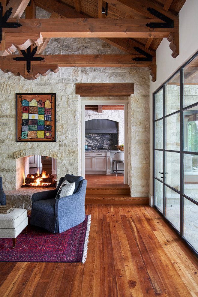 Photo of a mediterranean open concept living room in Austin with white walls, medium hardwood floors and exposed beam.