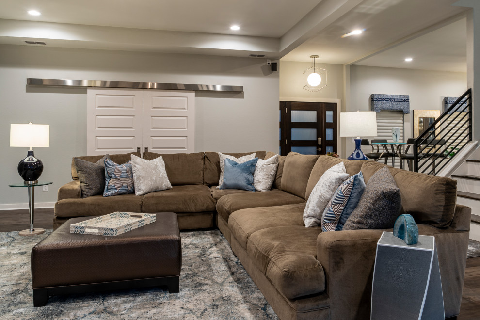 Inspiration for a mid-sized transitional open concept family room in Austin with grey walls, laminate floors, a standard fireplace, a wall-mounted tv and brown floor.